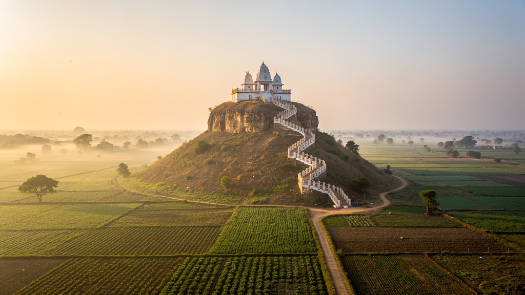 Chotila hill at dawn with the Chamunda Mataji temple at the summit above flat farmland