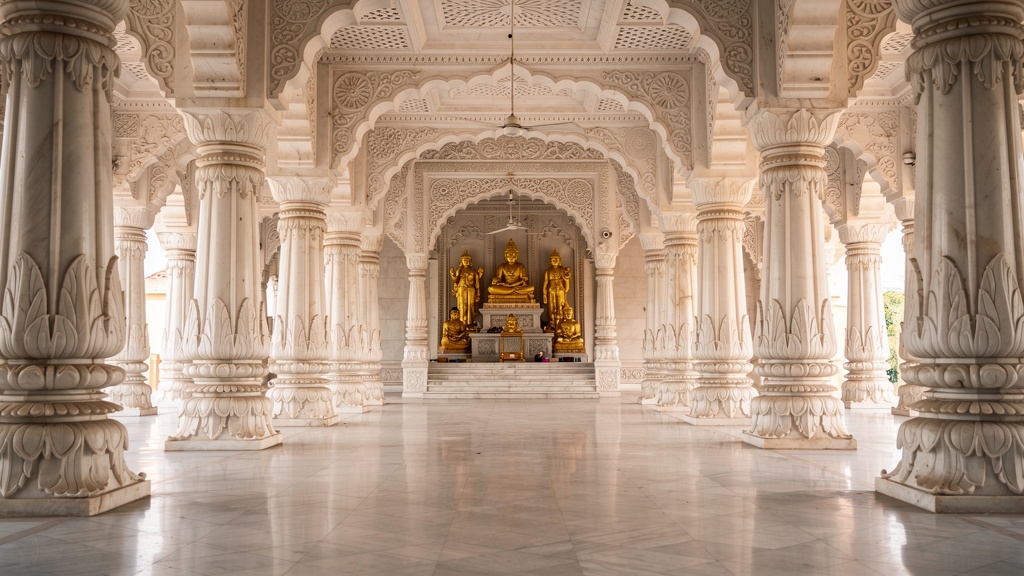 Interior marble hall with carved pillars and golden statues